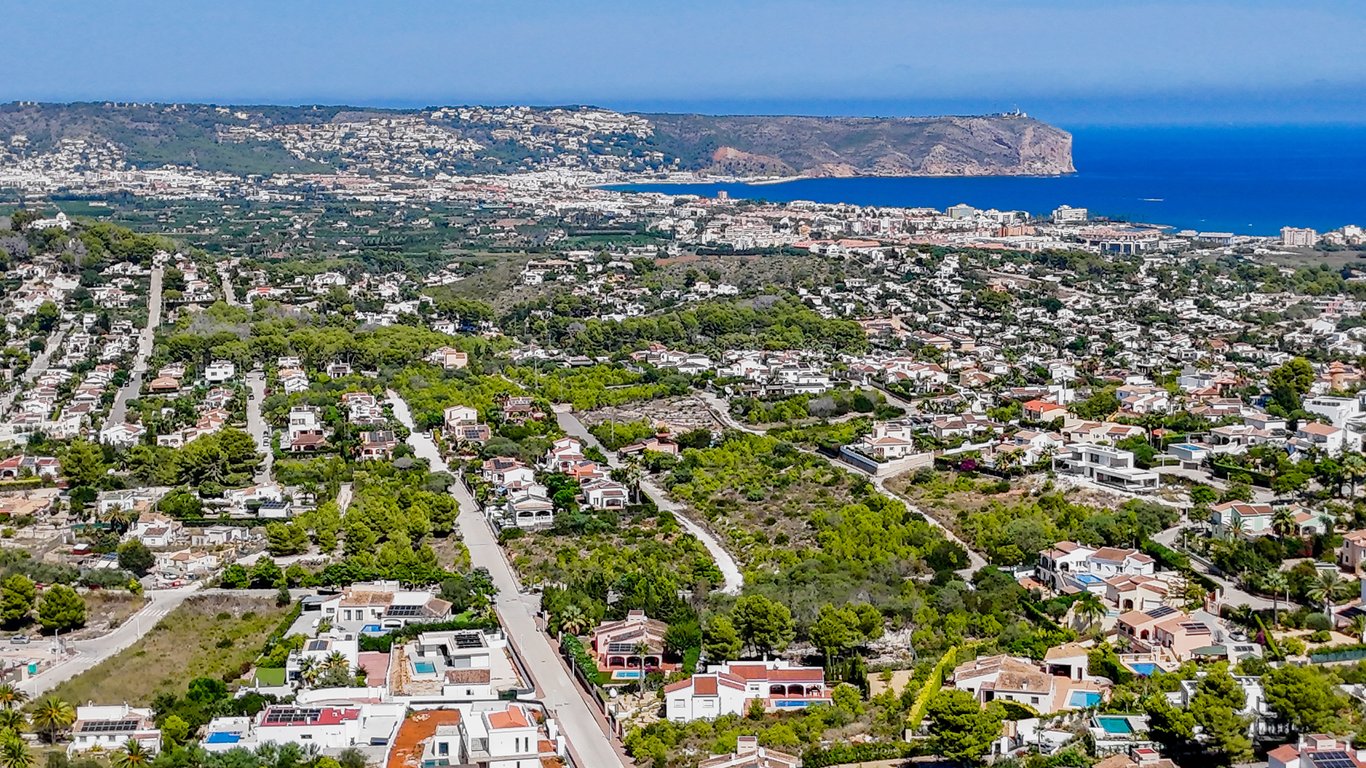 Panorama-Luftaufnahme von Jávea mit Blick auf das Mittelmeer, das Cabo de San Antonio und die in mediterranes Grün eingebetteten Wohngebiete.