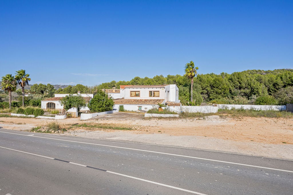 Außenansicht der traditionellen Finca mit weißen Fassaden und Terrakottadächern, direkt an der Zufahrtsstraße gelegen und von Pinienwäldern umgeben.