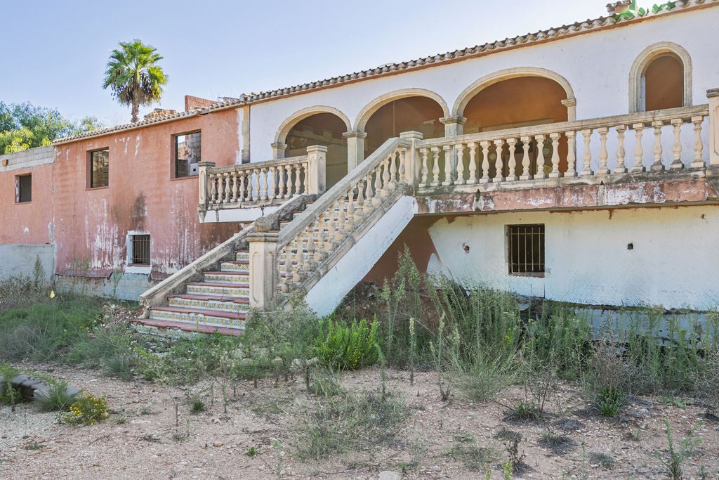 Außenfassade mit einer herrschaftlichen Steintreppe, verzierten Fliesenspiegeln und einer bogenförmigen Terrasse mit klassischer Steinbalustrade.