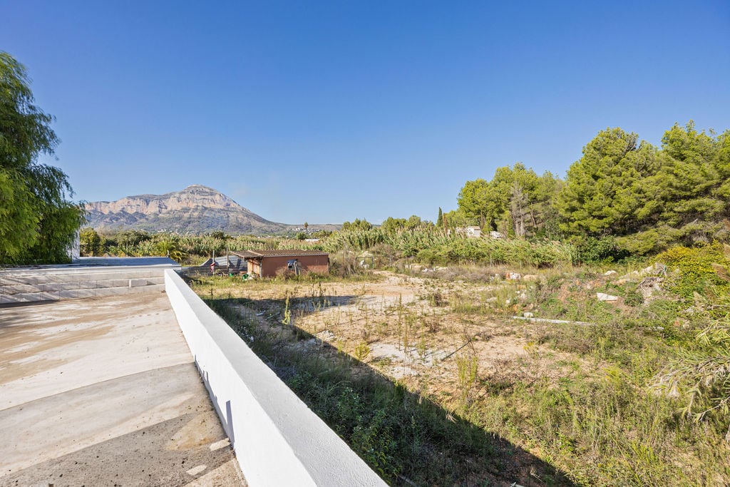 Panoramablick auf den Berg Montgó von einer erhöhten Betonplattform aus, mit Blick auf ein flaches Baugrundstück und mediterrane Vegetation.