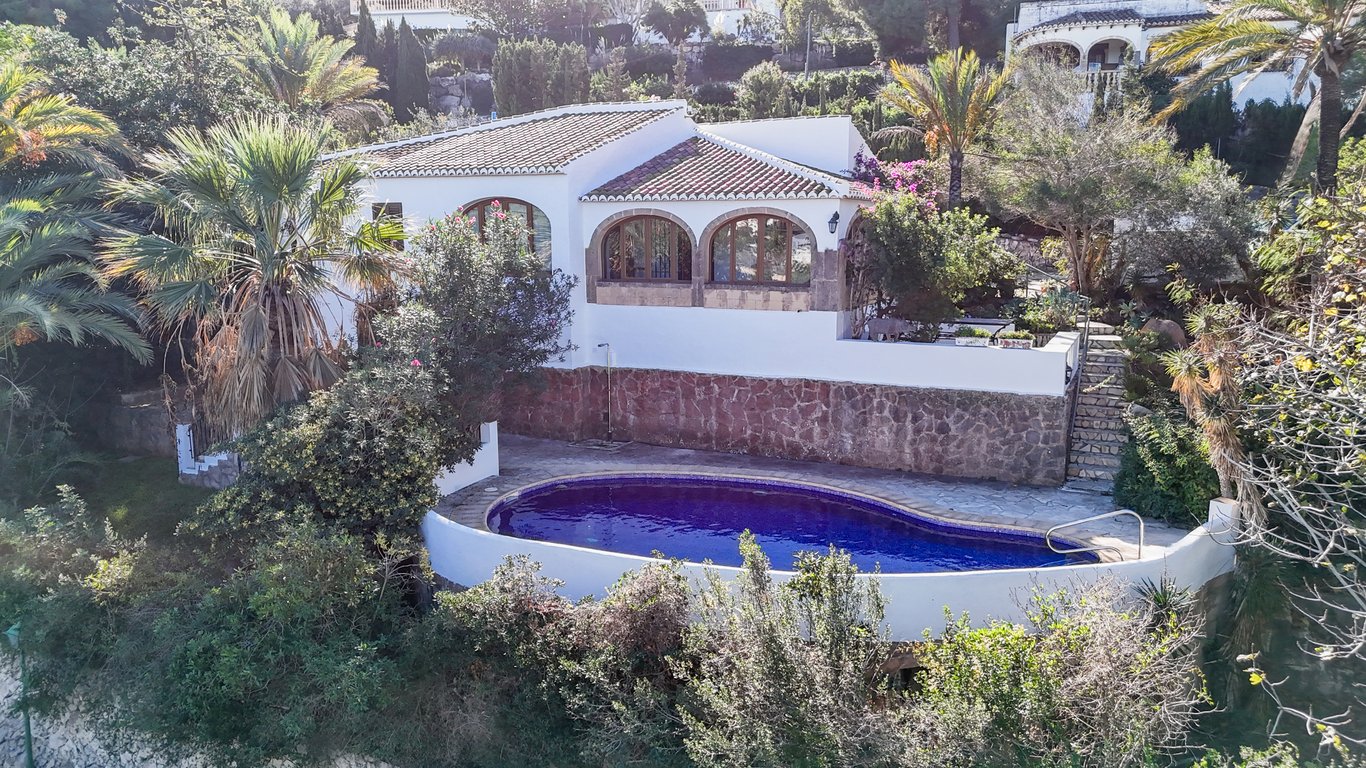 Außenansicht der Villa mit ovalem Privatpool, Natursteinmauern und einer traditionellen Naya mit Tosca-Steinbögen in mediterraner Umgebung.