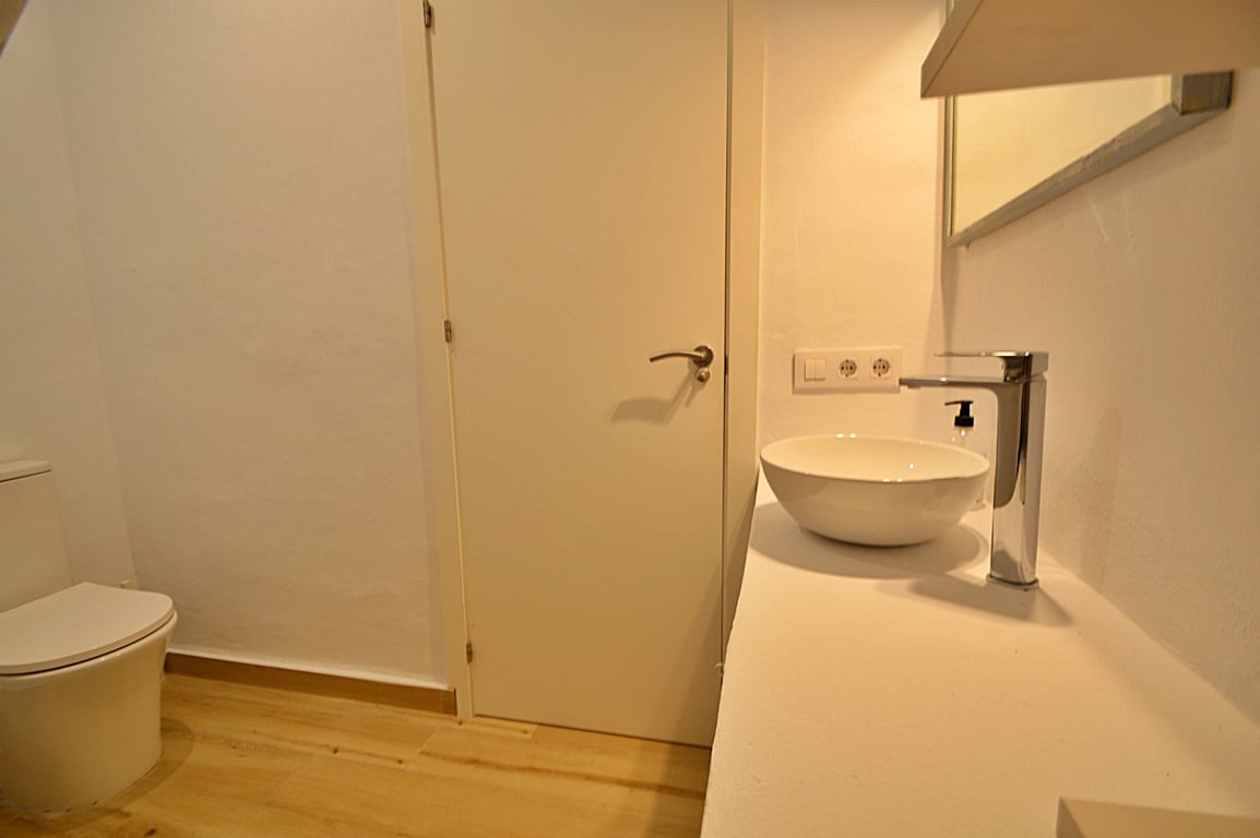 Modernes Badezimmer mit Aufsatzwaschbecken, verchromter Armatur und hellem Holzboden. Das minimalistische Design besticht durch weiße Wände und zeitgemäße Ausstattung.