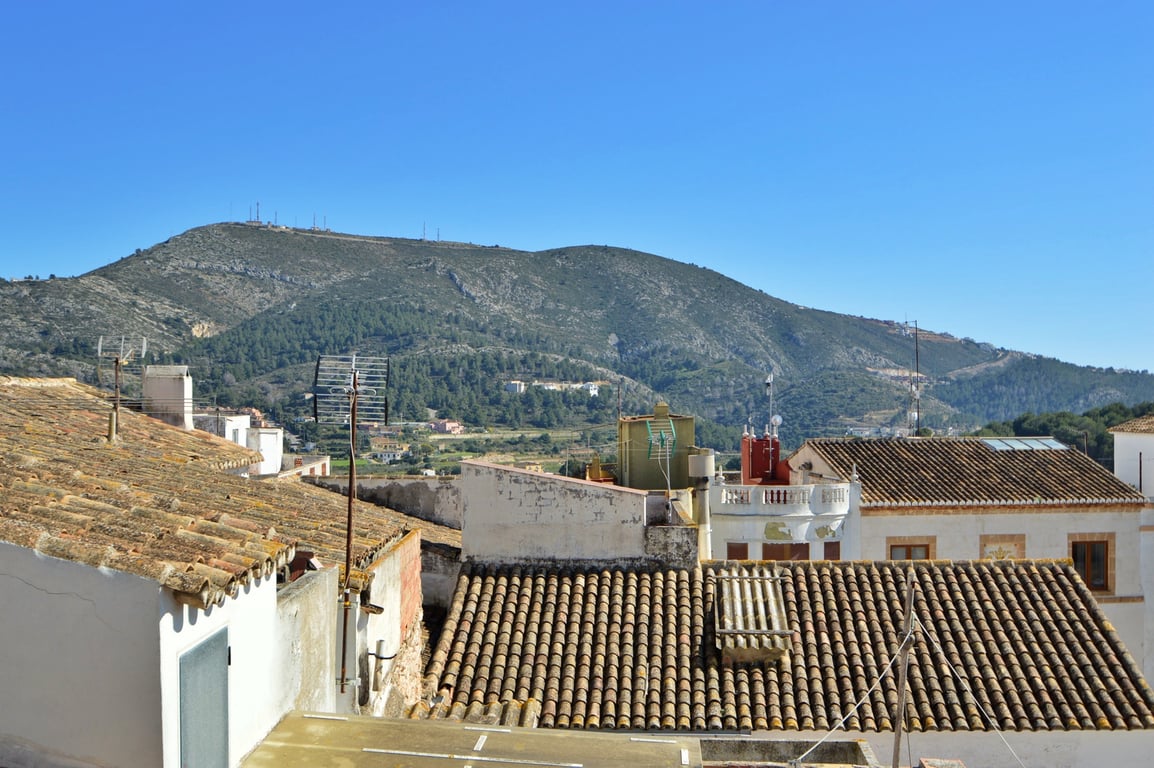 Panoramablick von der Dachterrasse auf die umliegenden Berge und die traditionellen Ziegeldächer des Dorfes.