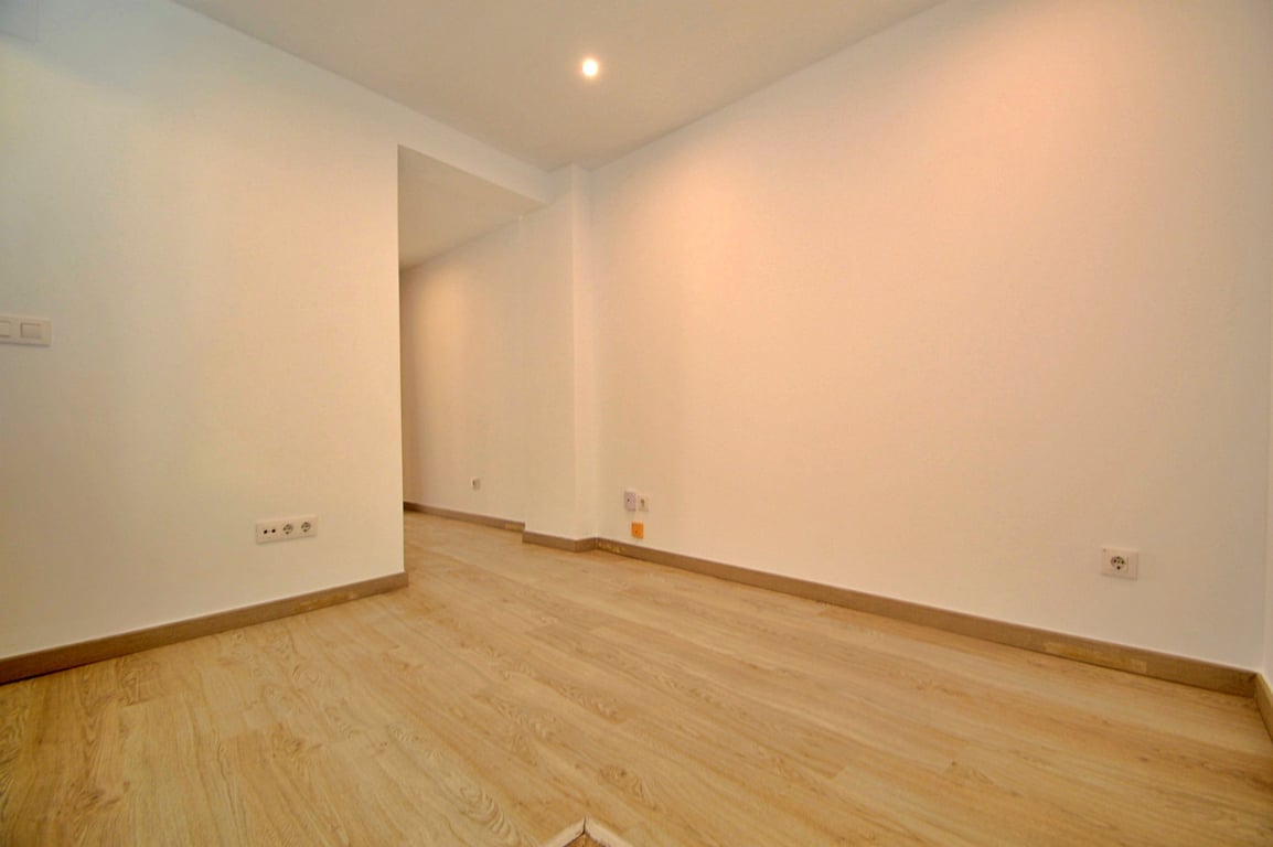 Renovierter Mehrzweckraum mit hellem Laminatboden in Holzoptik, glatten weißen Wänden und moderner Deckenbeleuchtung.
