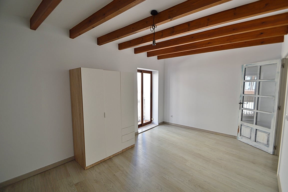 Renoviertes Zimmer mit originalen Holzbalkendecken, hellem Holzboden und Balkonzugang. Inklusive modernem Kleiderschrank und einer handgefertigten Holz-Glastür.