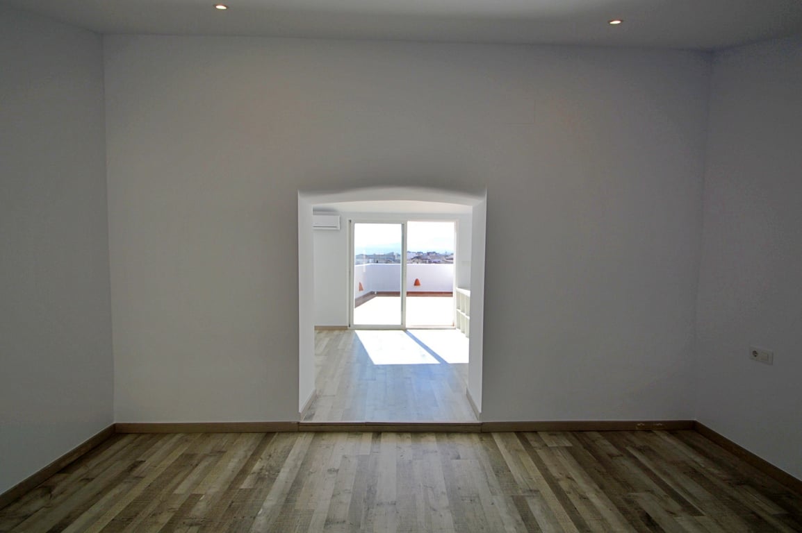 Vielseitiger Innenraum mit Laminatboden, Deckenspots und einem Rundbogen, der in einen hellen Bereich mit direktem Terrassenzugang führt.