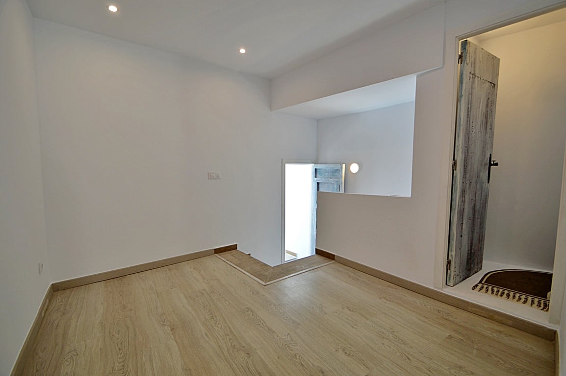 Vielseitiger Zwischenraum mit hellem Boden in Holzoptik, Deckeneinbaustrahlern und einer rustikalen, restaurierten Holztür.