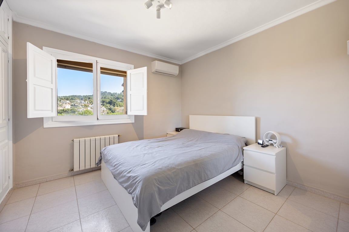 Helles Schlafzimmer mit weißen Fensterläden, Klimaanlage und weitem Blick auf die Landschaft von Jávea. Ausgestattet mit neutralen Tönen und Fliesenboden.