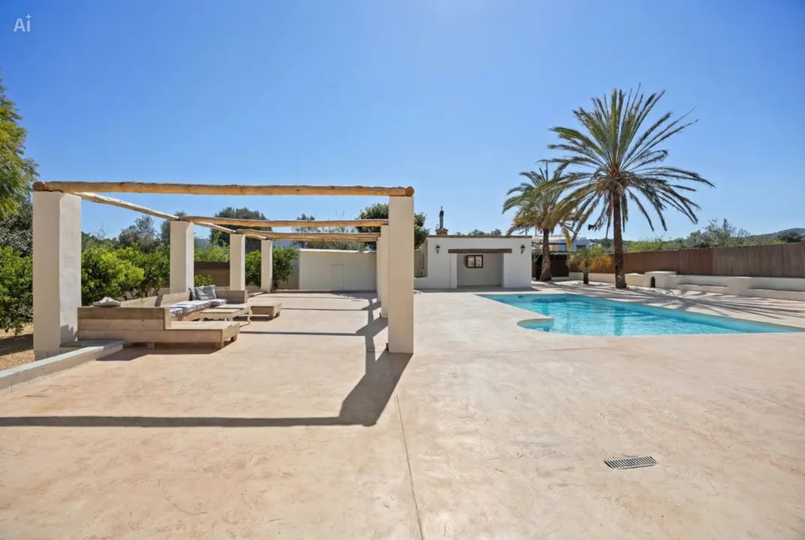 Poolbereich mit großzügiger gepflasterter Terrasse, rustikaler Holzbalken-Pergola und integrierten Sitzgelegenheiten inmitten mediterraner Gärten mit Palmen.