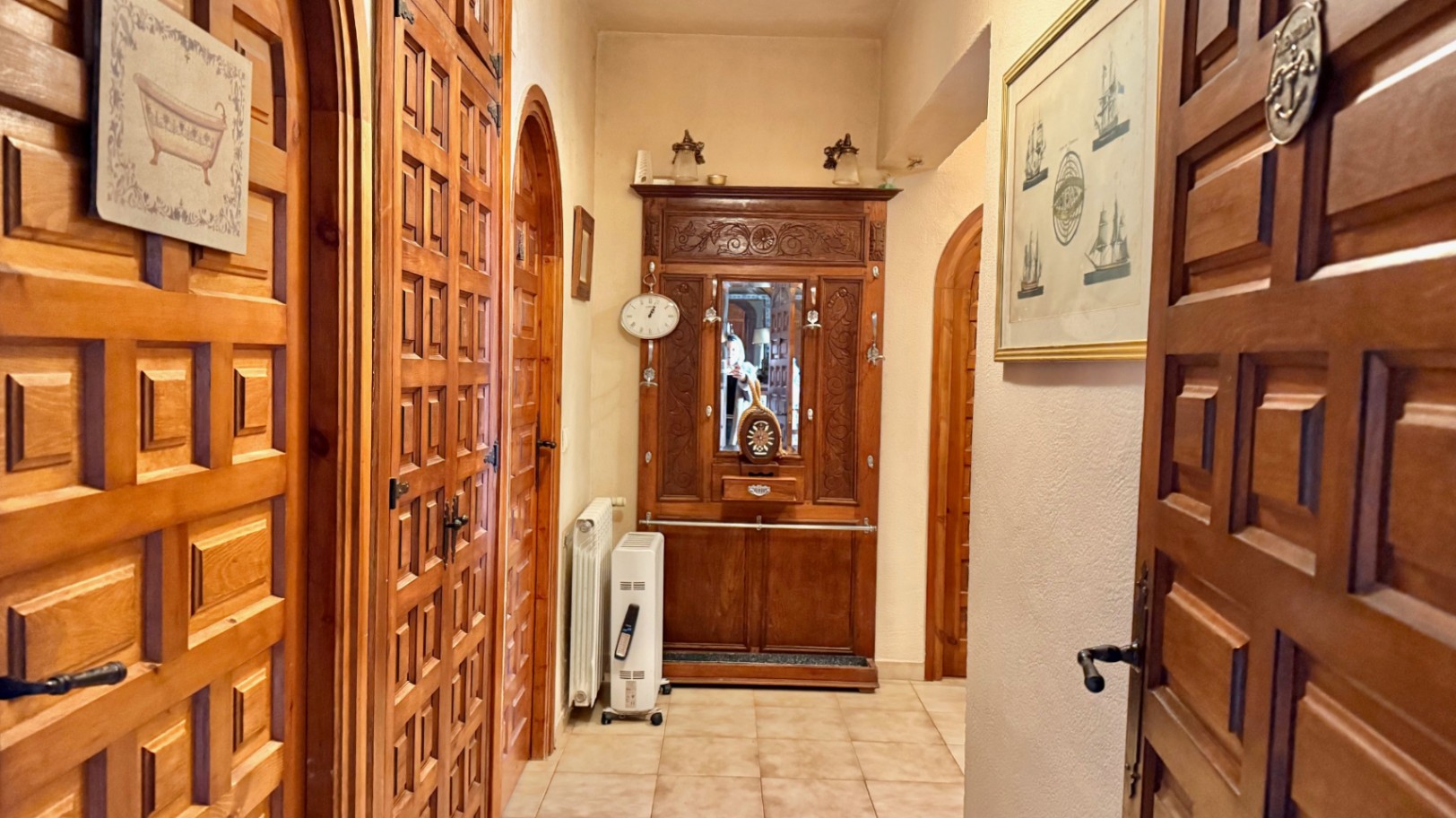 Innenflur mit traditionellen Kassettentüren aus Holz und Rundbögen. Ein geschnitzter Garderobenschrank und helle Fliesenböden prägen den klassischen Stil.