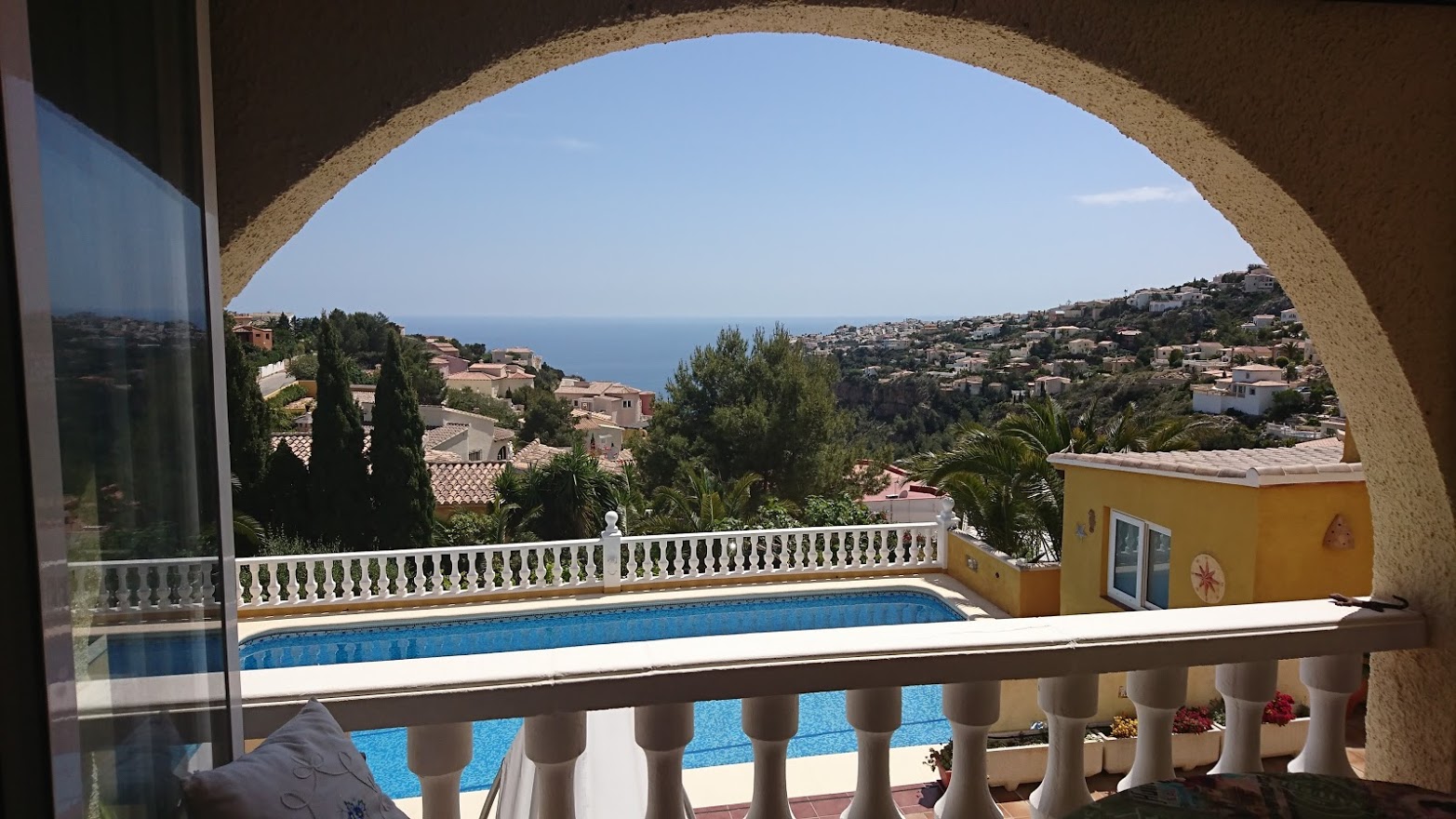 Panoramablick auf das Mittelmeer durch einen Rundbogen, mit Blick auf den privaten Pool und die klassischen weißen Balustraden.