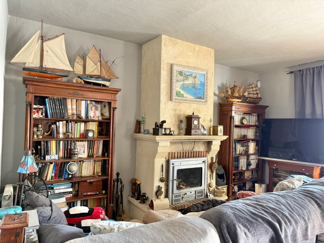 Traditionelles Wohnzimmer mit Steinkamin und Einsatz, flankiert von klassischen Holzregalen mit nautischer Dekoration und einer umfangreichen Buchsammlung.