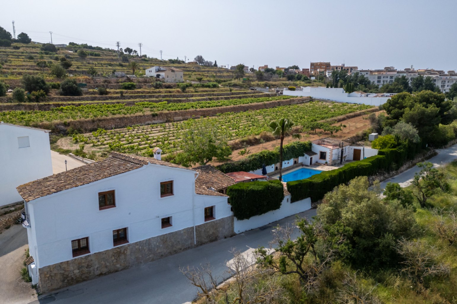 Luftaufnahme eines weißen Landhauses mit Pool, umgeben von Weinbergen in Teulada, Costa Blanca.
