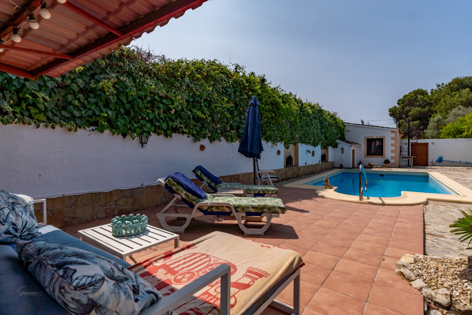 Poolblick mit Sonnenliegen und bewachsener Wand in Teulada.