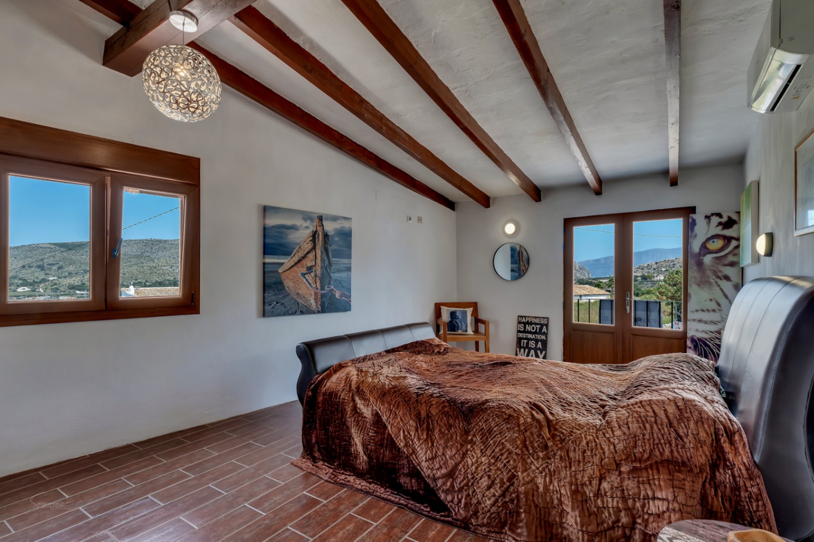Rustikales Schlafzimmer mit Holzbalken, Fliesenboden und Bergblick.