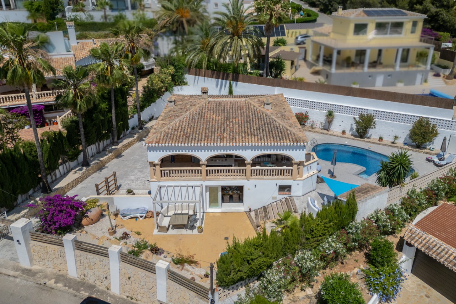 Luftaufnahme der Villa in Jávea mit überdachter Terrasse, blauem Pool und mediterranem Garten.