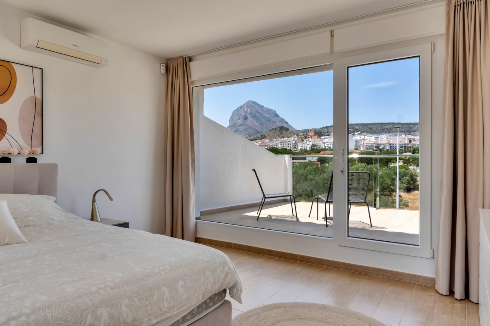 Hauptschlafzimmer mit privater Terrasse und weitem Blick auf den Berg Montgó. Ausgestattet mit Klimaanlage, hellen Bodenfliesen und großen Fensterfronten.