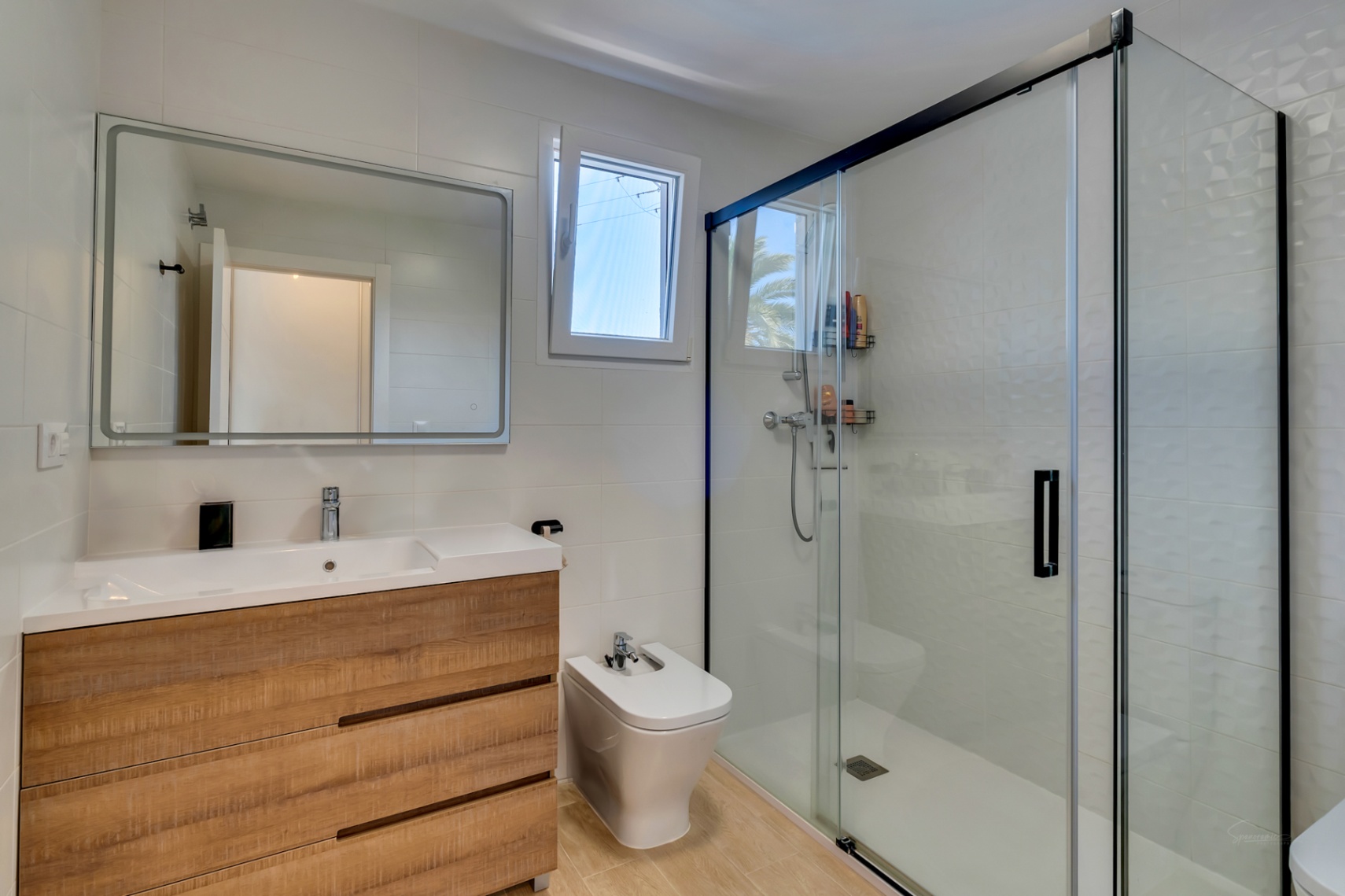 Modernes Badezimmer mit Holz-Waschtisch, Bidet und einer geräumigen begehbaren Dusche mit schwarz gerahmten Glastüren und strukturierten Fliesen.