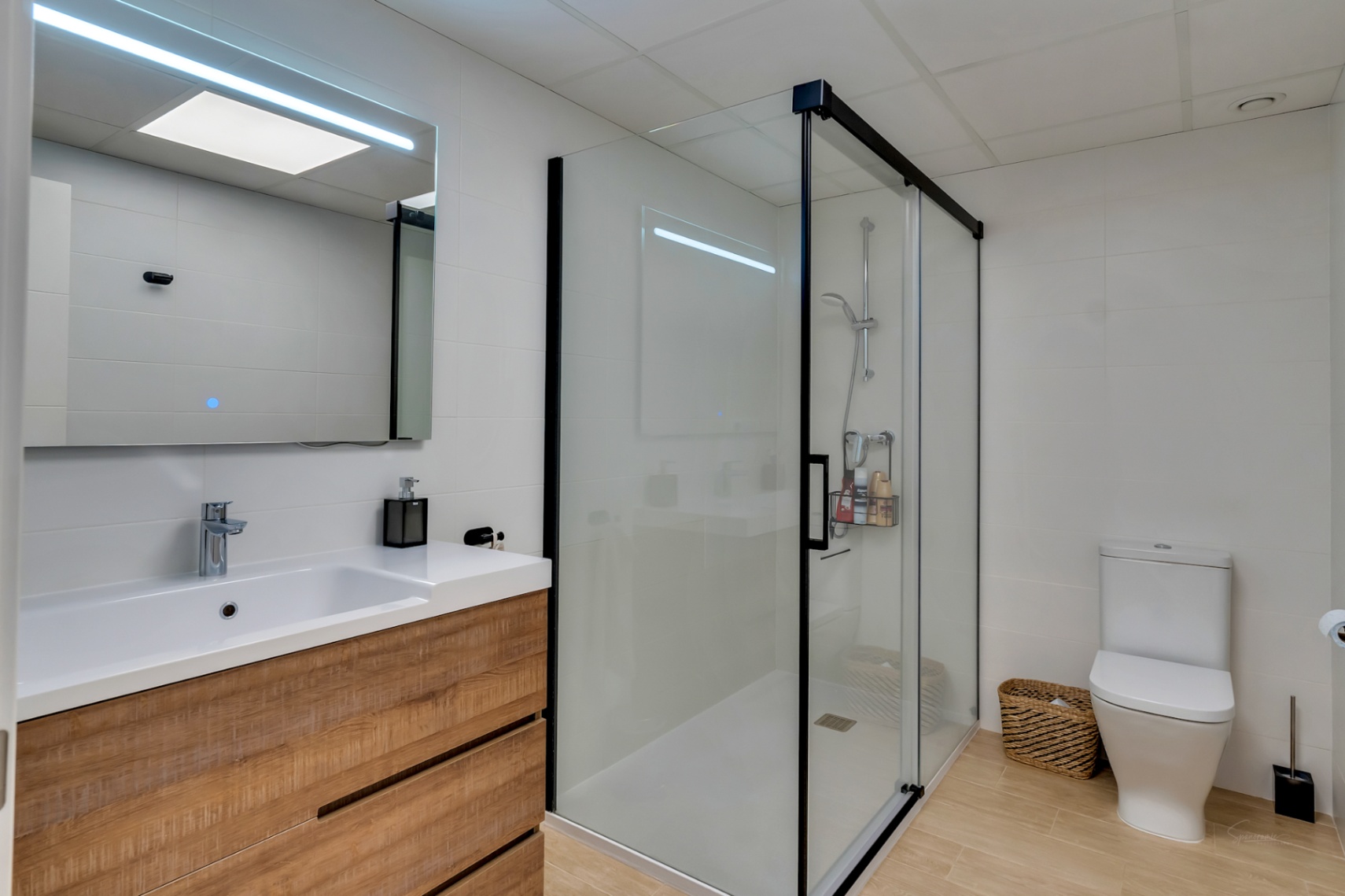 Modernes Badezimmer mit Holzwaschtisch, LED-Spiegel und begehbarer Dusche mit schwarzem Rahmen sowie Bodenfliesen in warmer Holzoptik.