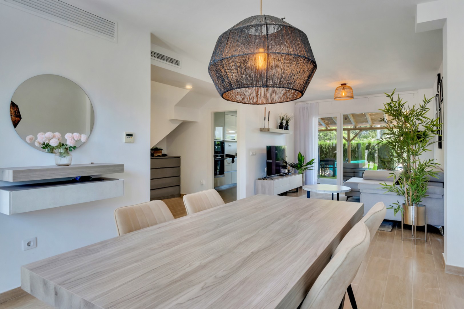 Offener Wohn- und Essbereich mit modernem Holztisch, Design-Pendelleuchte und direktem Zugang zur privaten Terrasse mit Pergola.