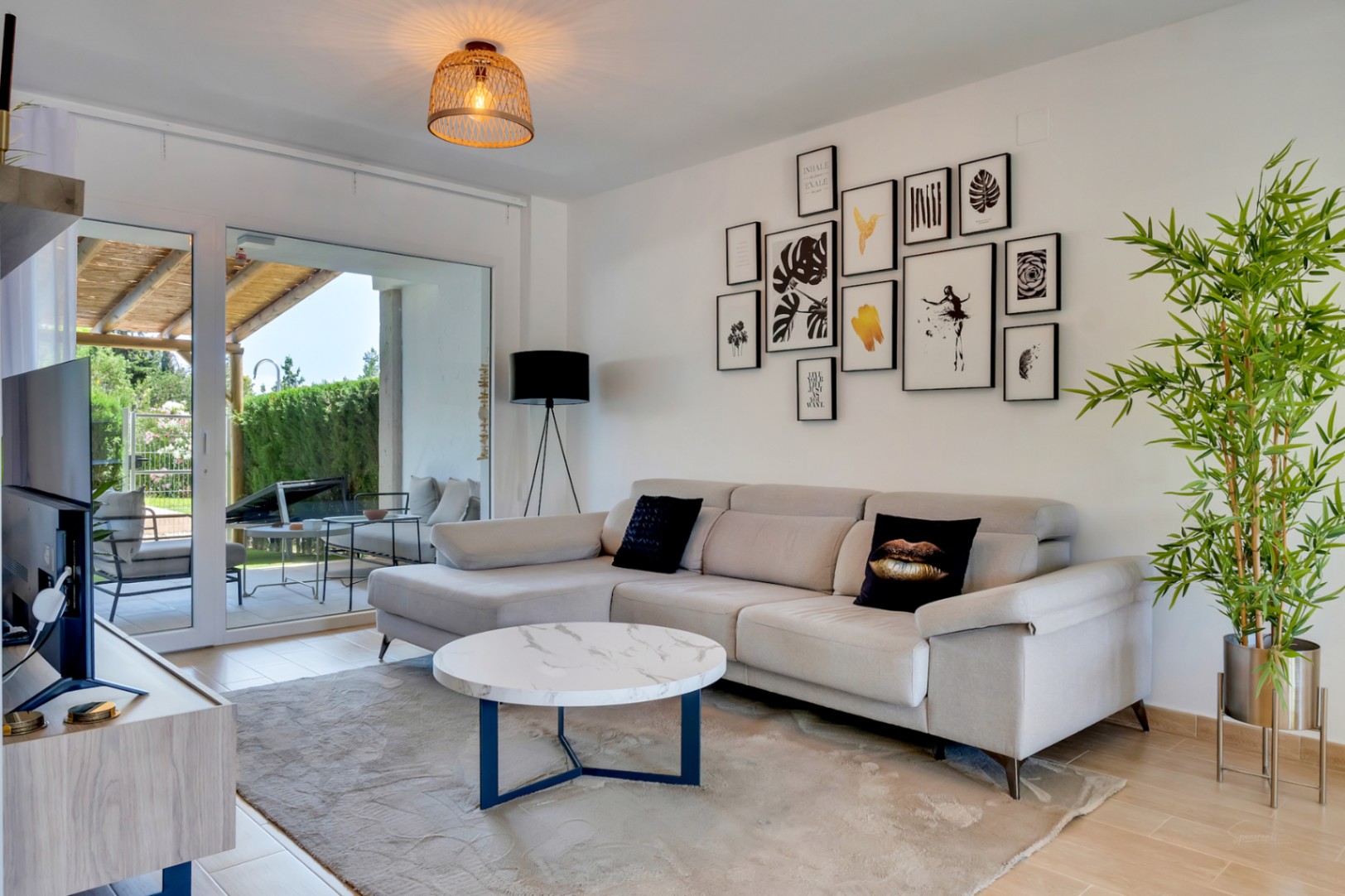 Offener Wohnbereich mit modernem Ecksofa, Marmortisch und großen Glasschiebetüren, die direkt auf die private Terrasse führen.