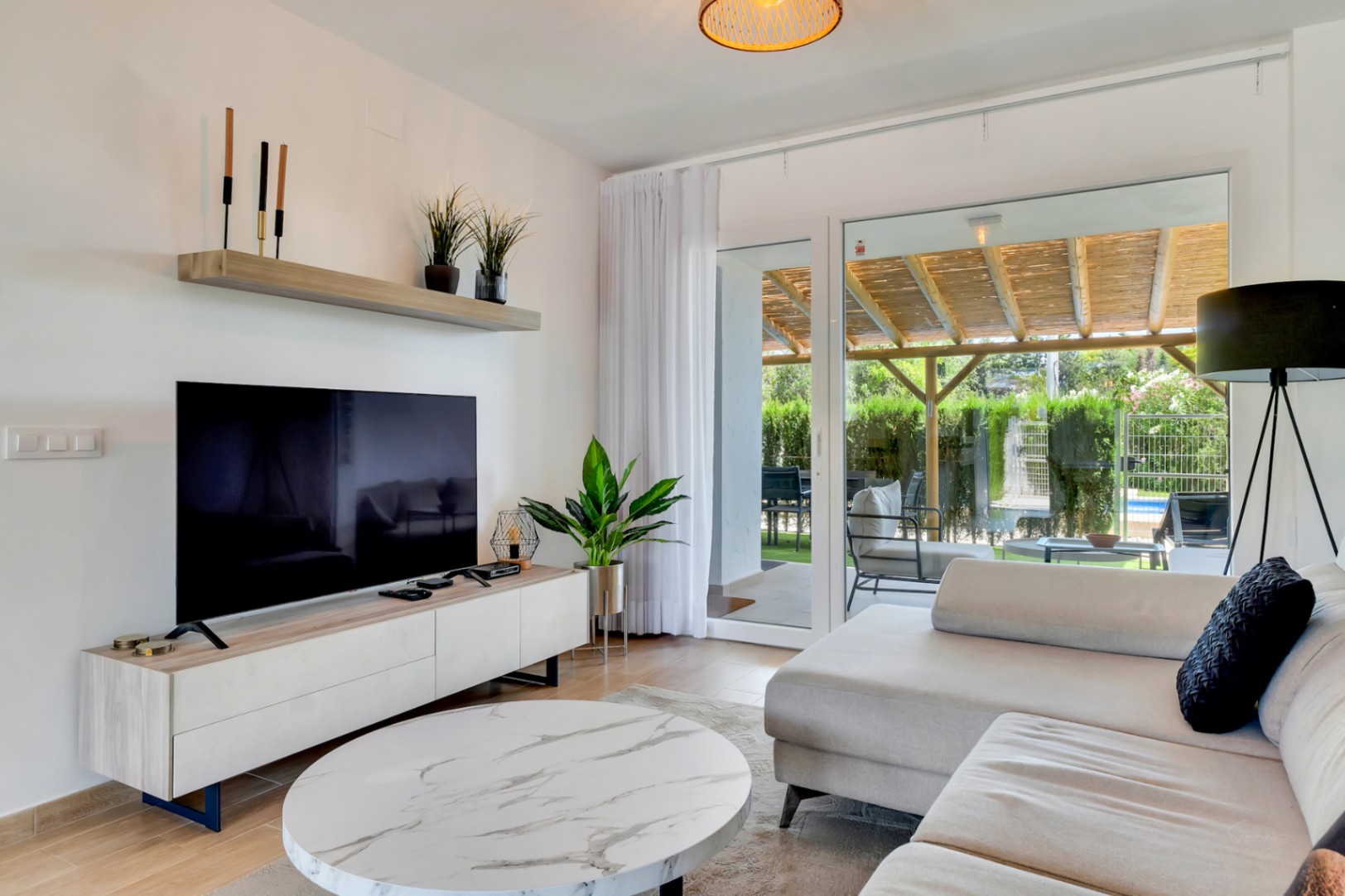 Offener Wohnbereich mit modernen Möbeln und großen Glasschiebetüren, die direkt auf die private Terrasse mit Holzpergola führen.