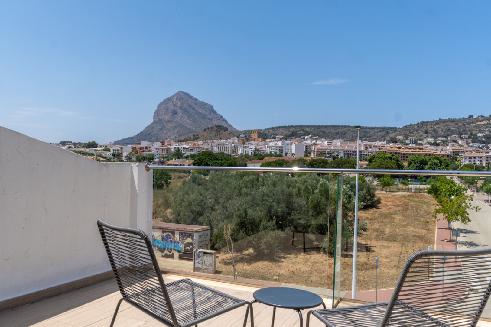 Private Dachterrasse mit Panoramablick auf den Montgó und die Altstadt von Jávea, ausgestattet mit modernen Sitzmöbeln und einem Glasgeländer.