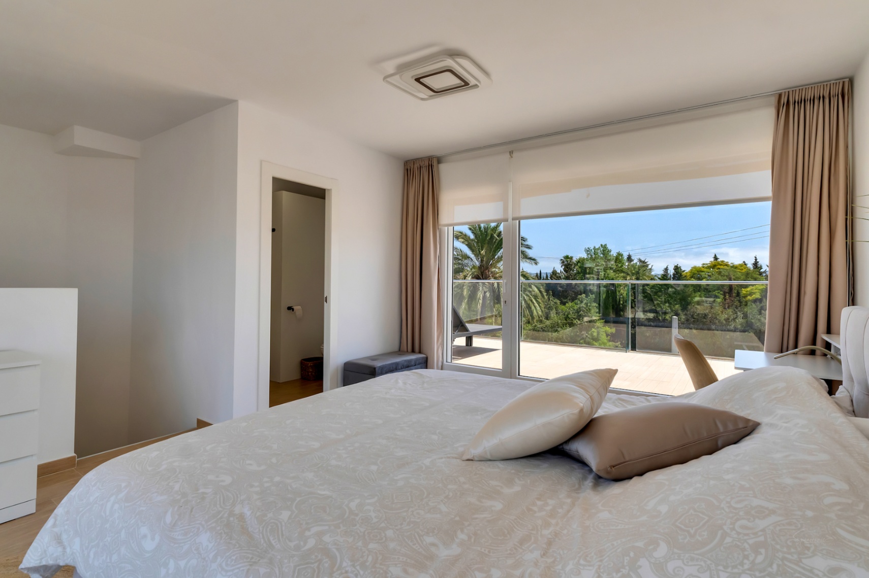 Schlafzimmer im Obergeschoss mit direktem Zugang zu einer privaten Terrasse, bodentiefen Fenstern und integriertem En-Suite-Badezimmer.