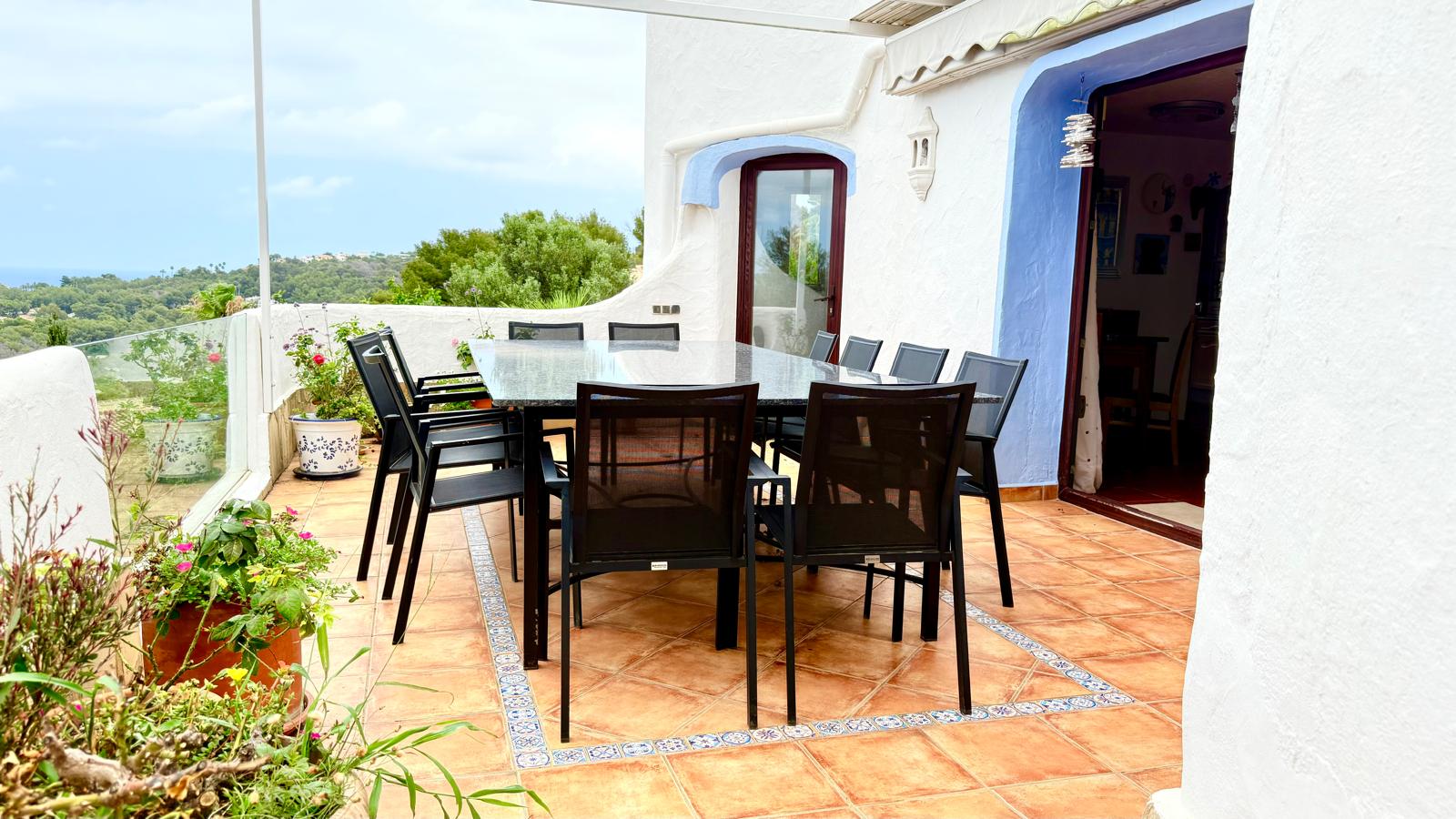 Außen-Essbereich auf der Terrasse mit Granittisch, Terrakottaboden mit Zierborten und weitem Blick über die mediterrane Umgebung.
