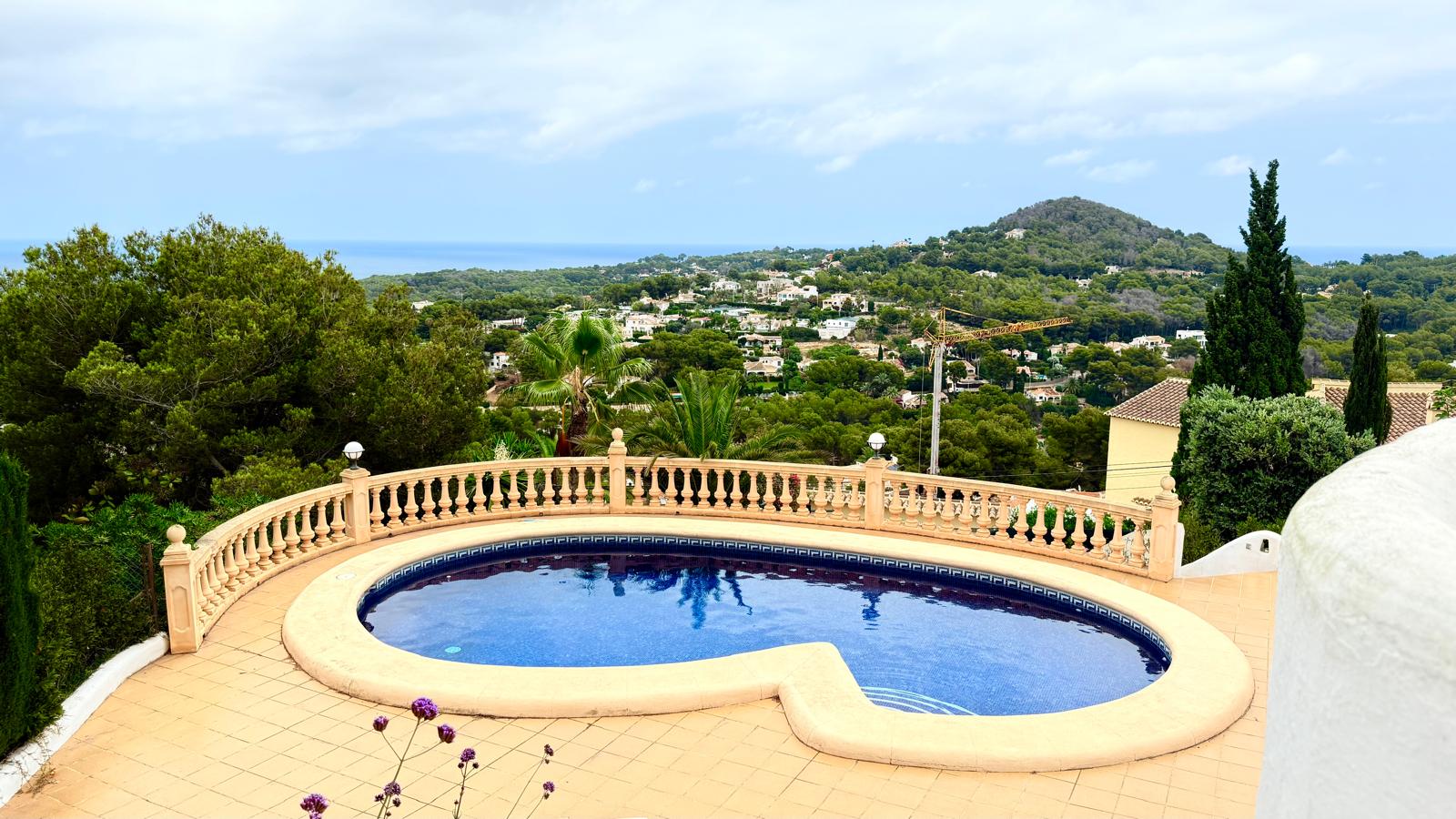 Nierenförmiger Privatpool mit blauen Mosaikfliesen und klassischer Steinbalustrade, der einen weiten Panoramablick auf das Mittelmeer und die Küste bietet.