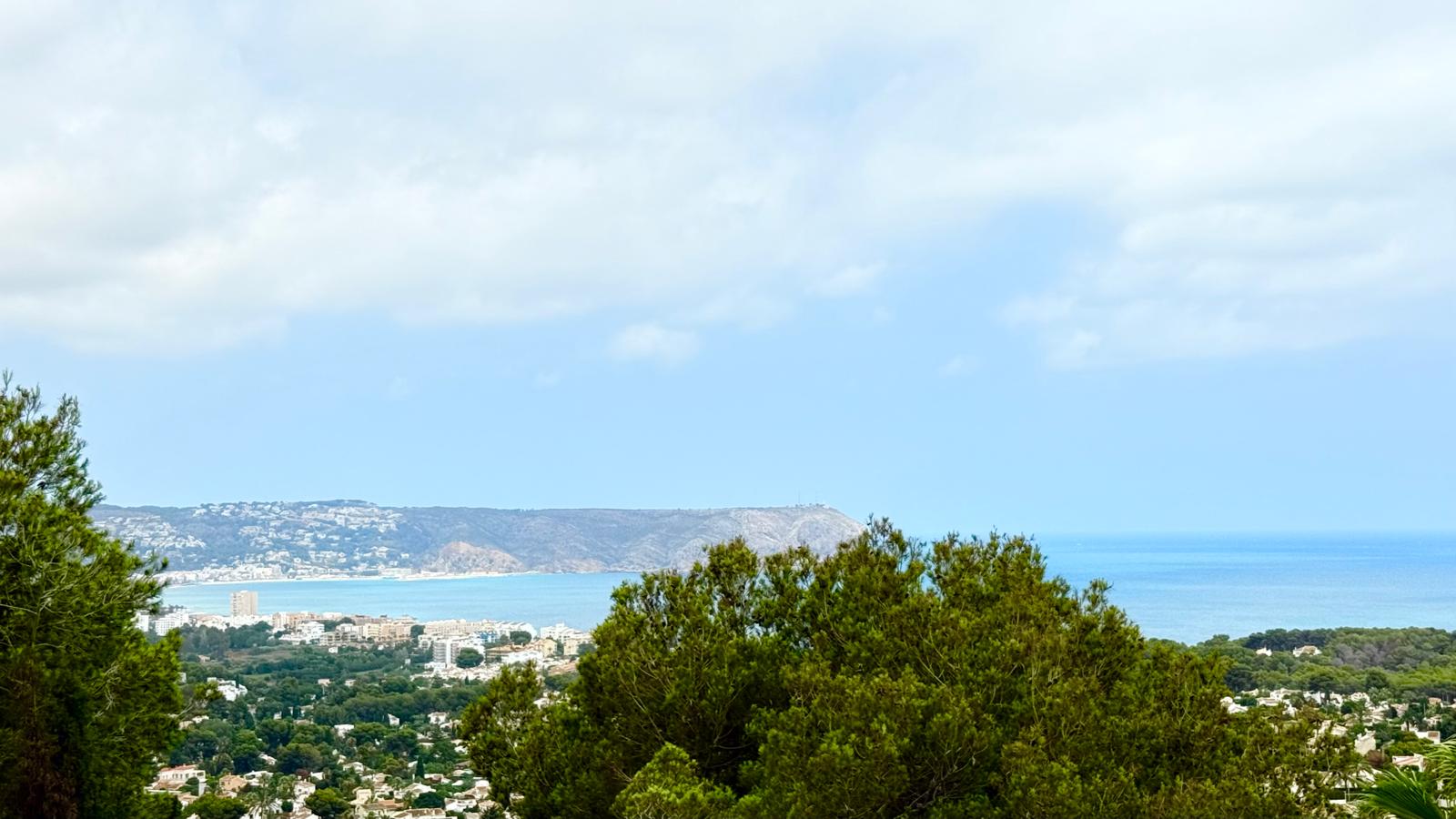 Panoramablick auf die Bucht von Jávea und das Cabo de San Antonio, eingerahmt von mediterranen Pinien von der erhöhten Lage des Anwesens aus.