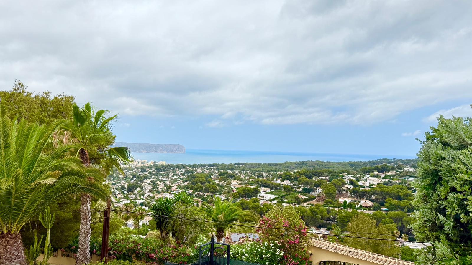 Panoramablick über die Bucht von Jávea und das Mittelmeer von der erhöhten Lage der Villa, umgeben von Palmen und reifer Vegetation.