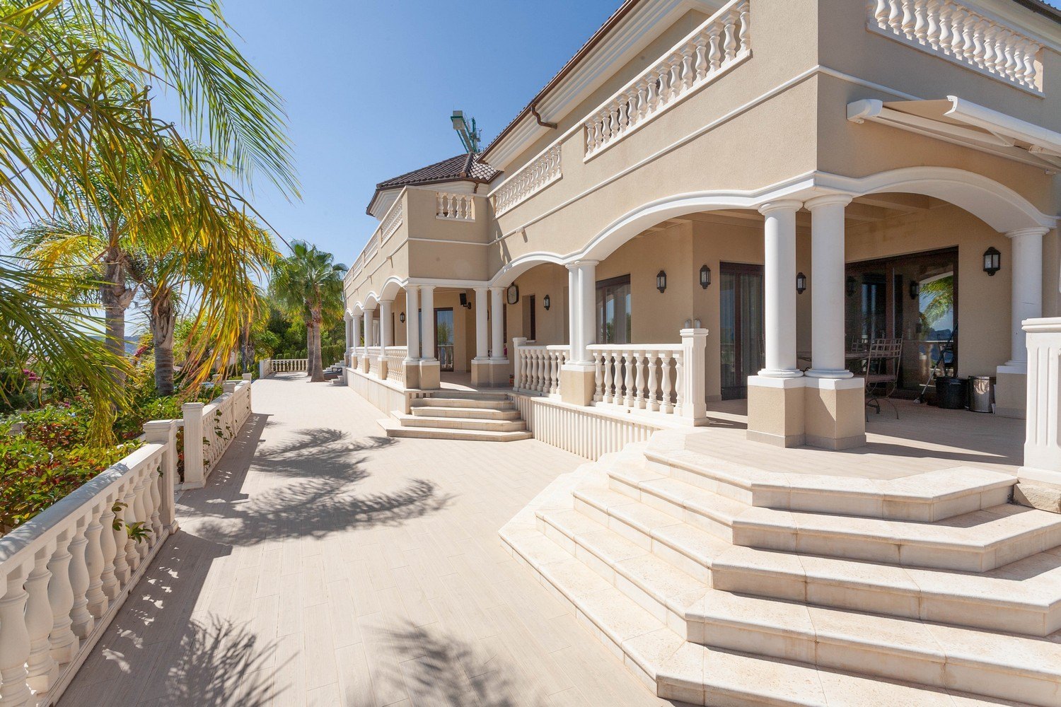 Außenansicht der Villa mit Steinterrasse und klassischem Geländer.