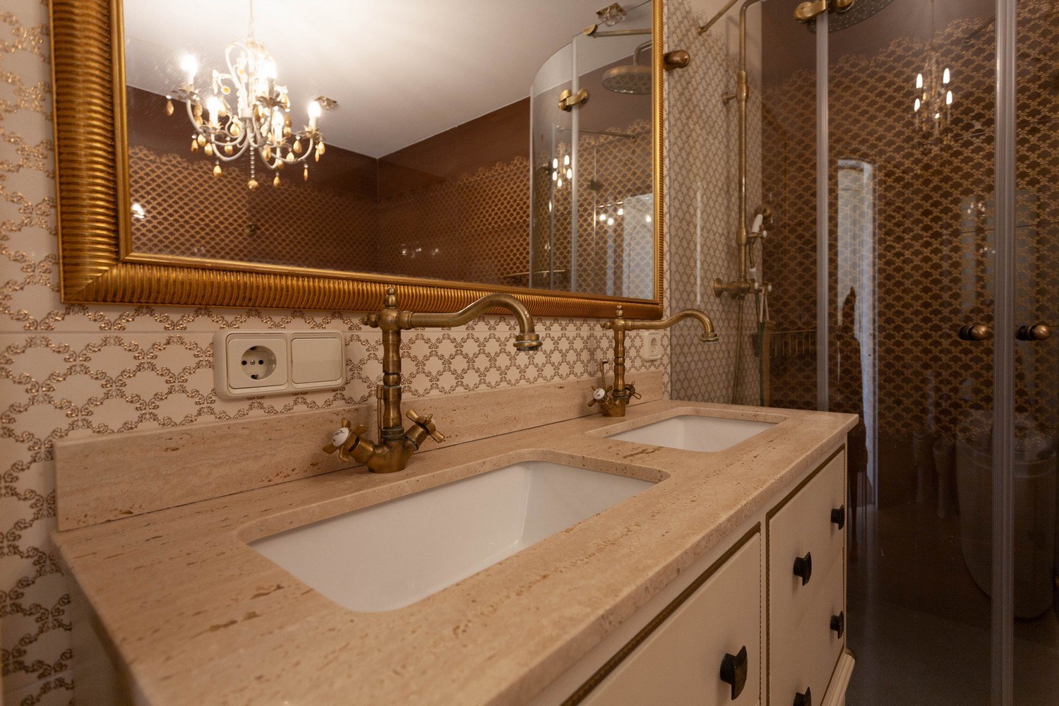 Badezimmerdetail mit Doppelwaschbecken aus Marmor und Messingarmaturen.