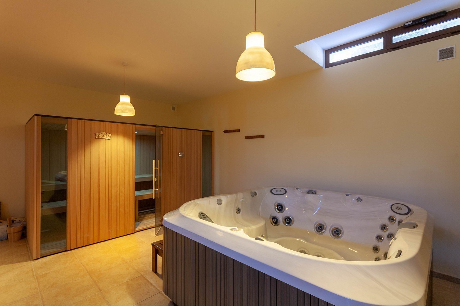 Detail des Whirlpools und der hellen Holzsauna mit Glastür.