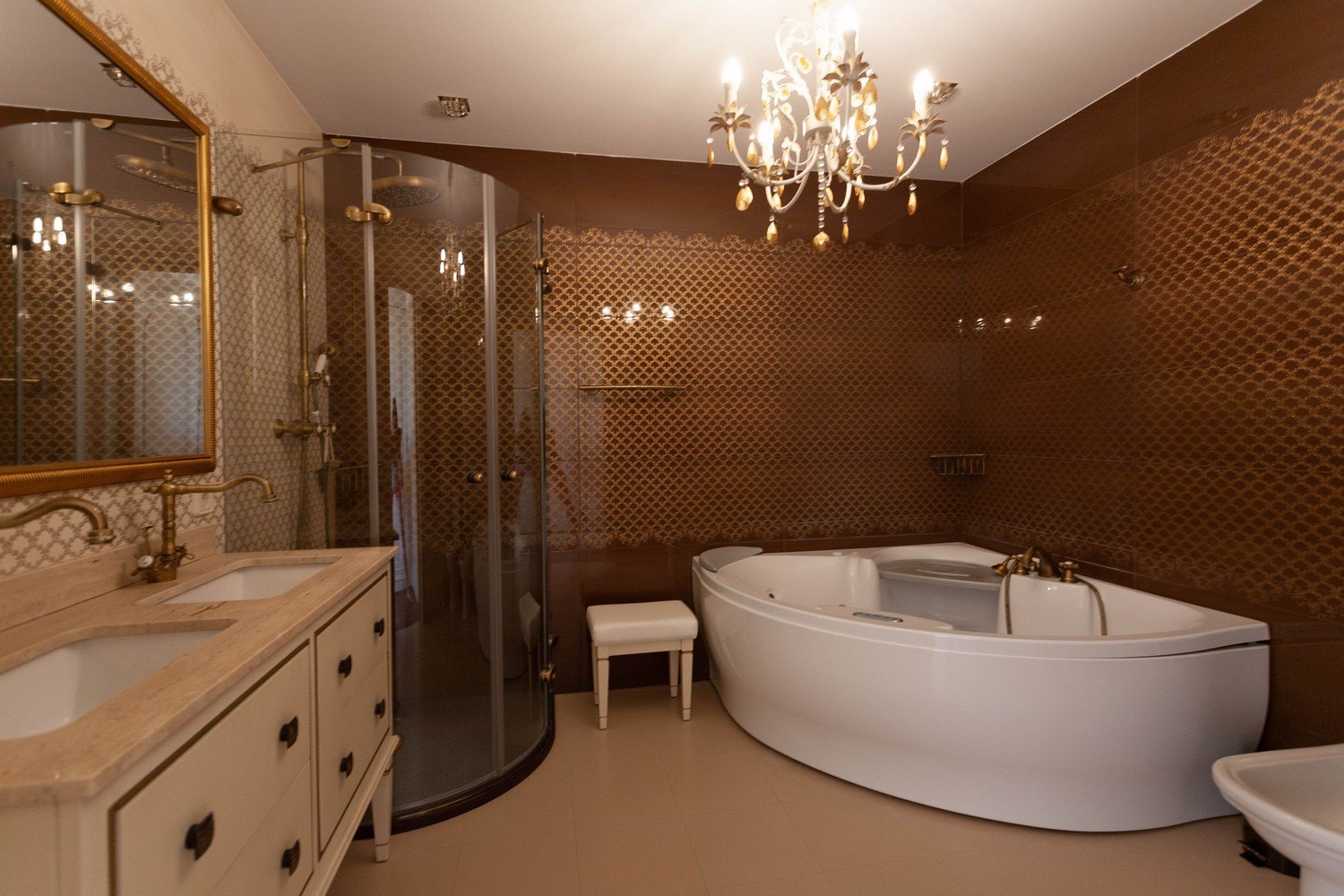 Elegantes Badezimmer mit Whirlpool, gebogener Glasdusche und Doppelwaschtisch mit goldenen Armaturen.