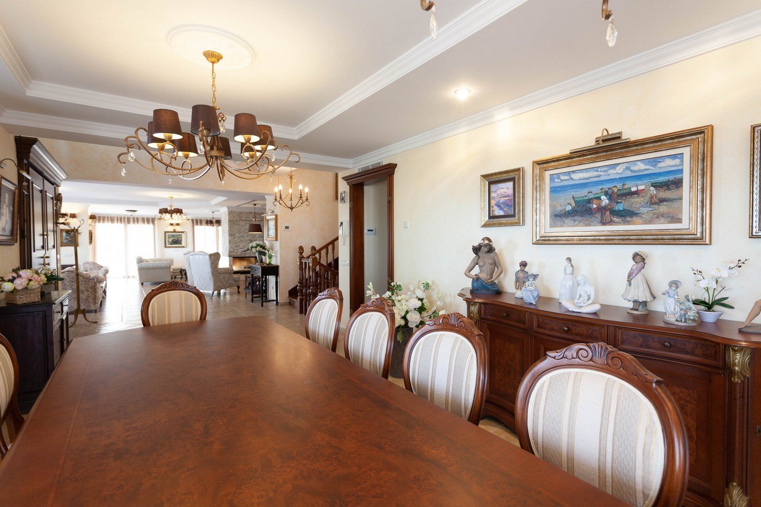 Esszimmer mit dunklem Holztisch, gepolsterten Stühlen und klassischem Sideboard mit dekorativen Skulpturen.