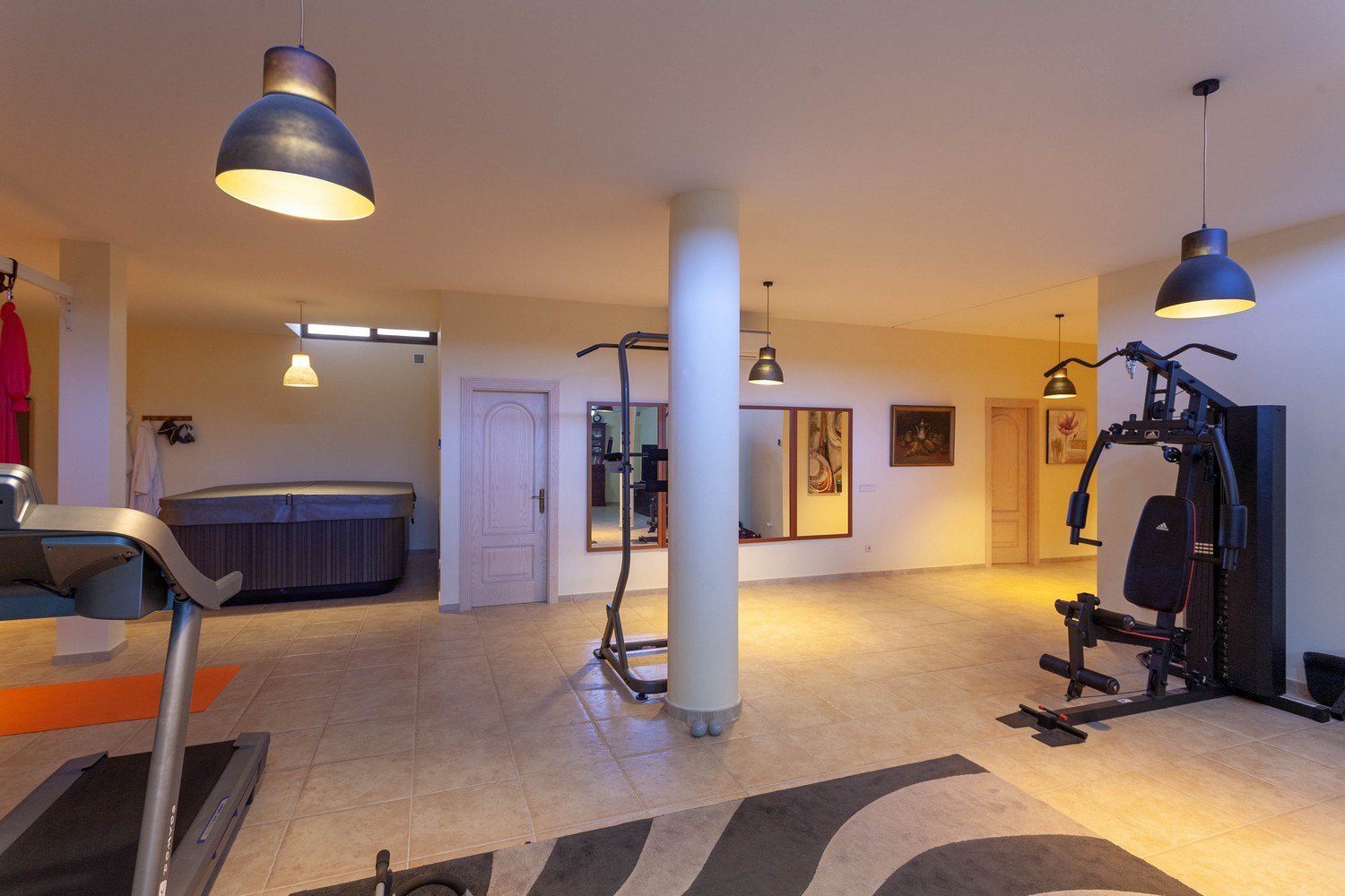 Fitnessraum mit Whirlpool, cremefarbenen Fliesenboden und warmer Ambientebeleuchtung.