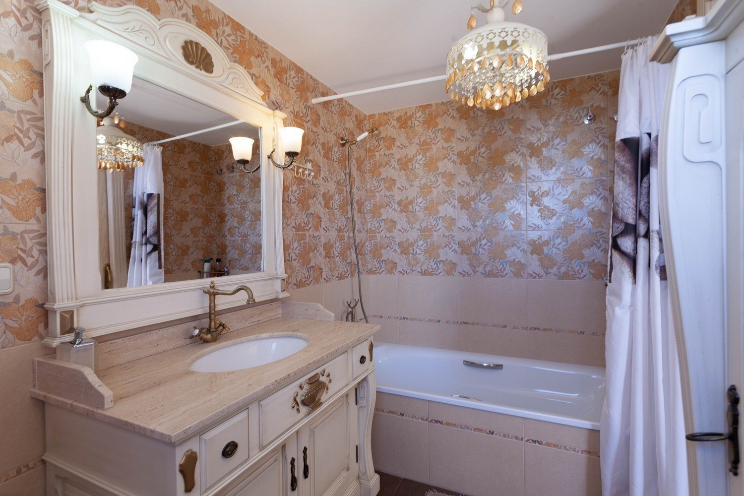 Klassisches Badezimmer mit Marmorwaschtisch, verziertem Spiegel und Badewanne mit Dusche.