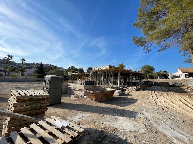 Villabau in Moraira: Betonstruktur mit Metallstützen unter blauem Himmel.
