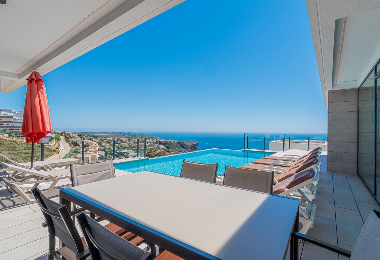 Hauptterrasse mit Infinity-Pool, Essbereich im Freien und Panoramablick auf das Mittelmeer und die Küstenfelsen von Cumbre del Sol.