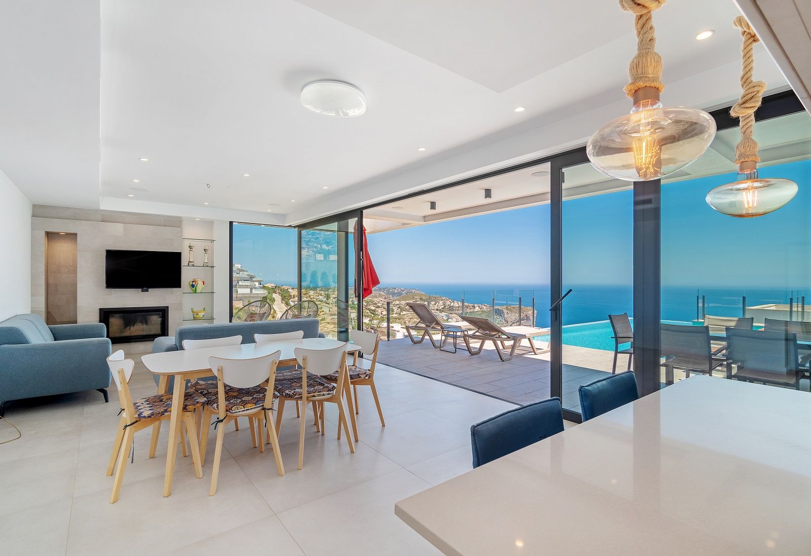 Offener Wohn- und Essbereich mit großen Glasschiebetüren, die direkt zur Terrasse mit Infinity-Pool und weitem Blick auf das Mittelmeer führen.