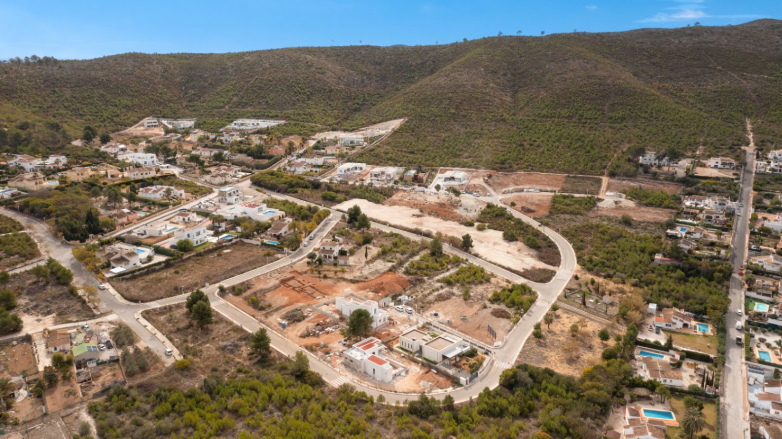 Luftaufnahme der Urbanisation Lomas Del Rey in Jávea mit modernen Villen vor einer beeindruckenden Bergkulisse und mediterraner Vegetation.