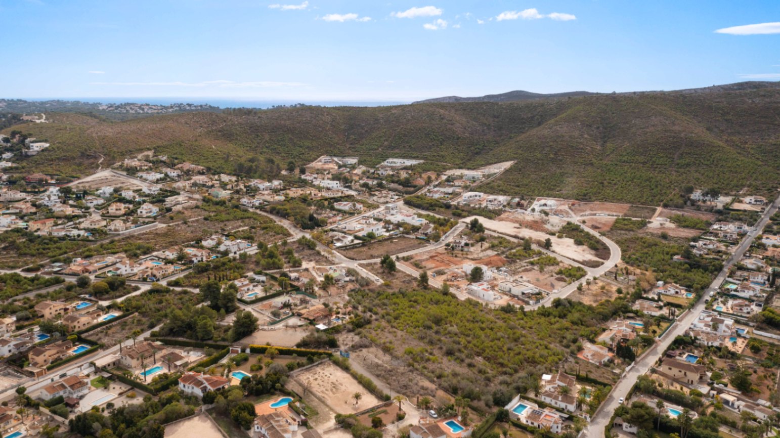 Luftaufnahme des Wohngebiets Lomas Del Rey in Jávea mit Blick auf die Villen, privaten Pools und die umliegende Hügellandschaft bis hin zum Mittelmeer.