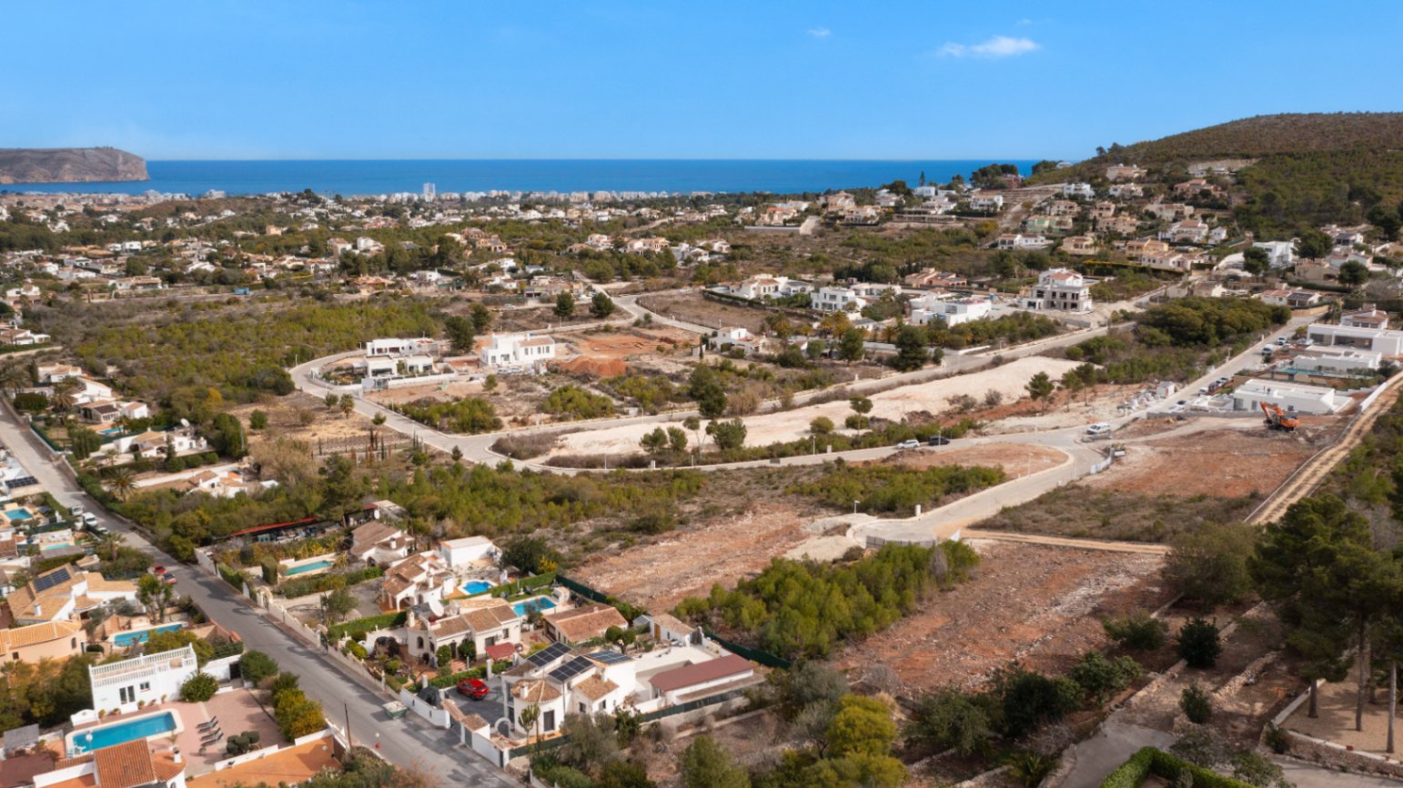 Panorama-Luftaufnahme des Wohngebiets in Jávea mit Blick auf das Mittelmeer, die umliegende Vegetation und die typische Küstenarchitektur.