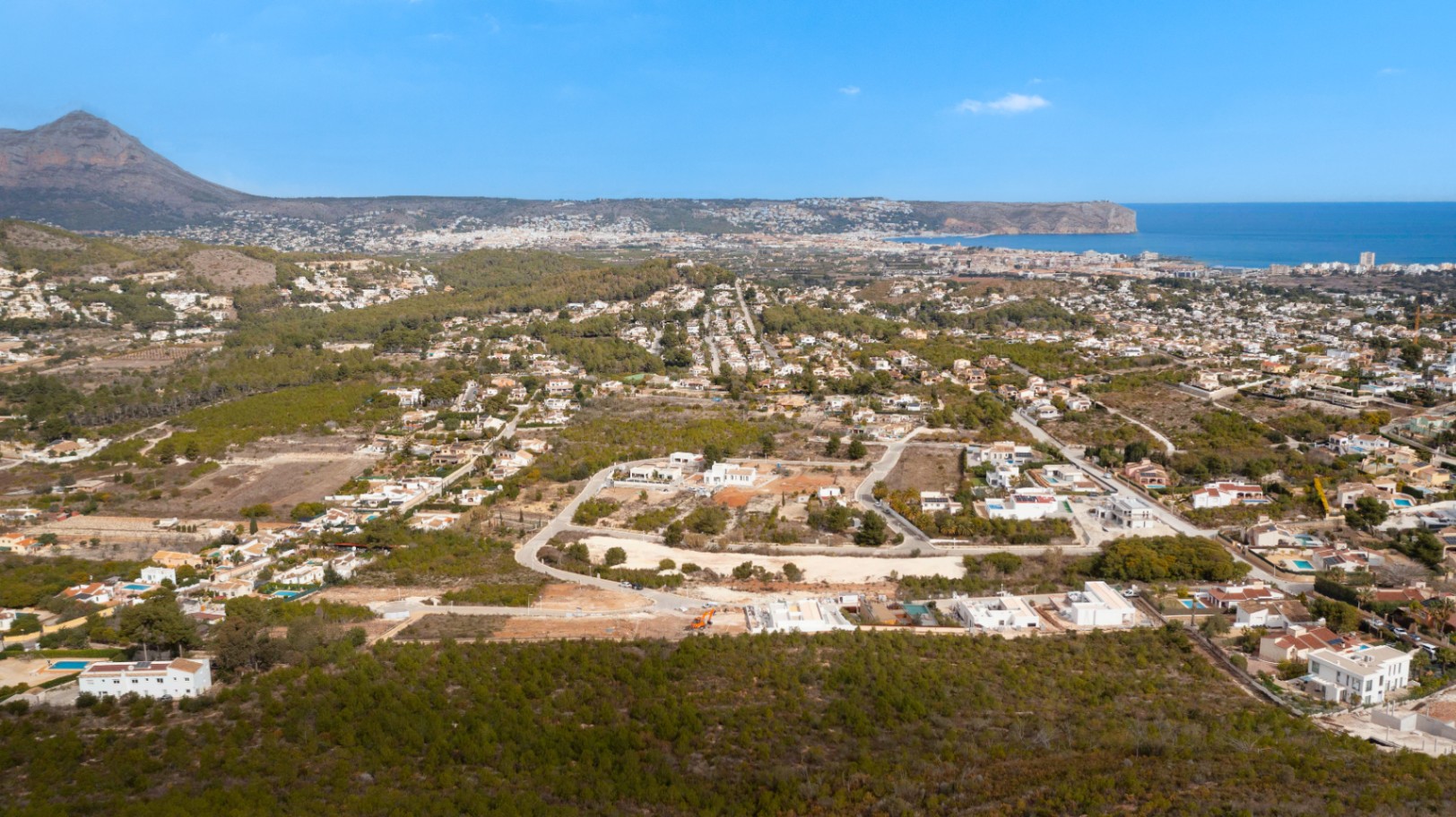 Panorama-Luftaufnahme von Lomas Del Rey mit Blick auf den Berg Montgó und die Mittelmeerküste inmitten einer grünen Wohngegend.