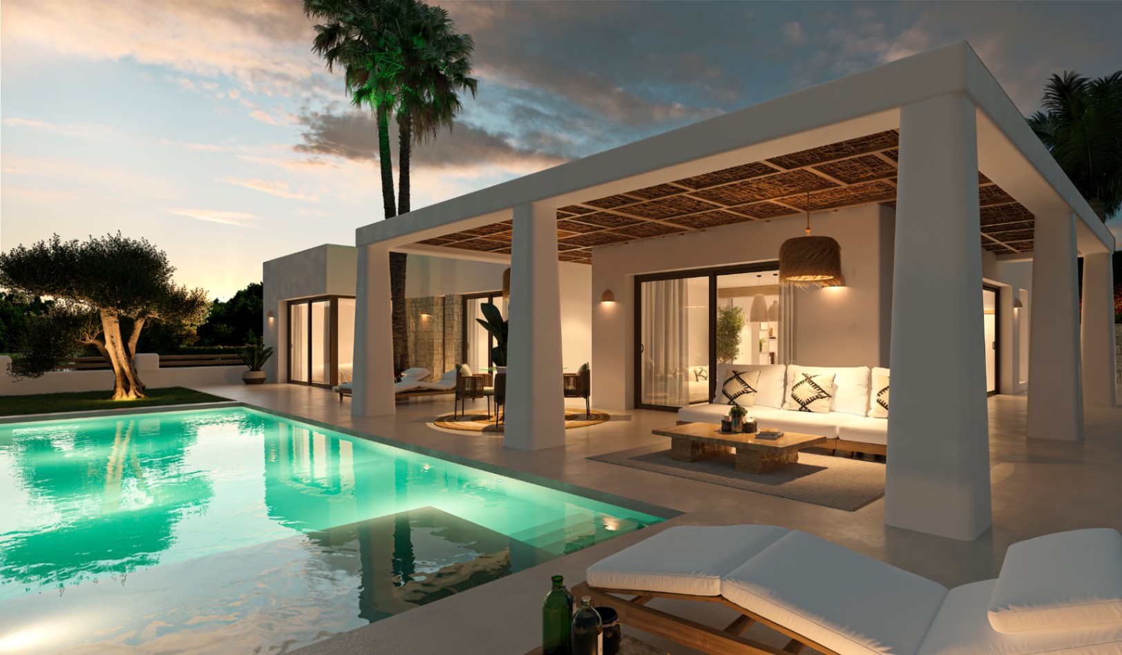 Außenansicht einer Villa im Ibiza-Stil mit beleuchtetem Pool, überdachter Terrasse mit Naturrohrdecke und Loungebereich bei Dämmerung.