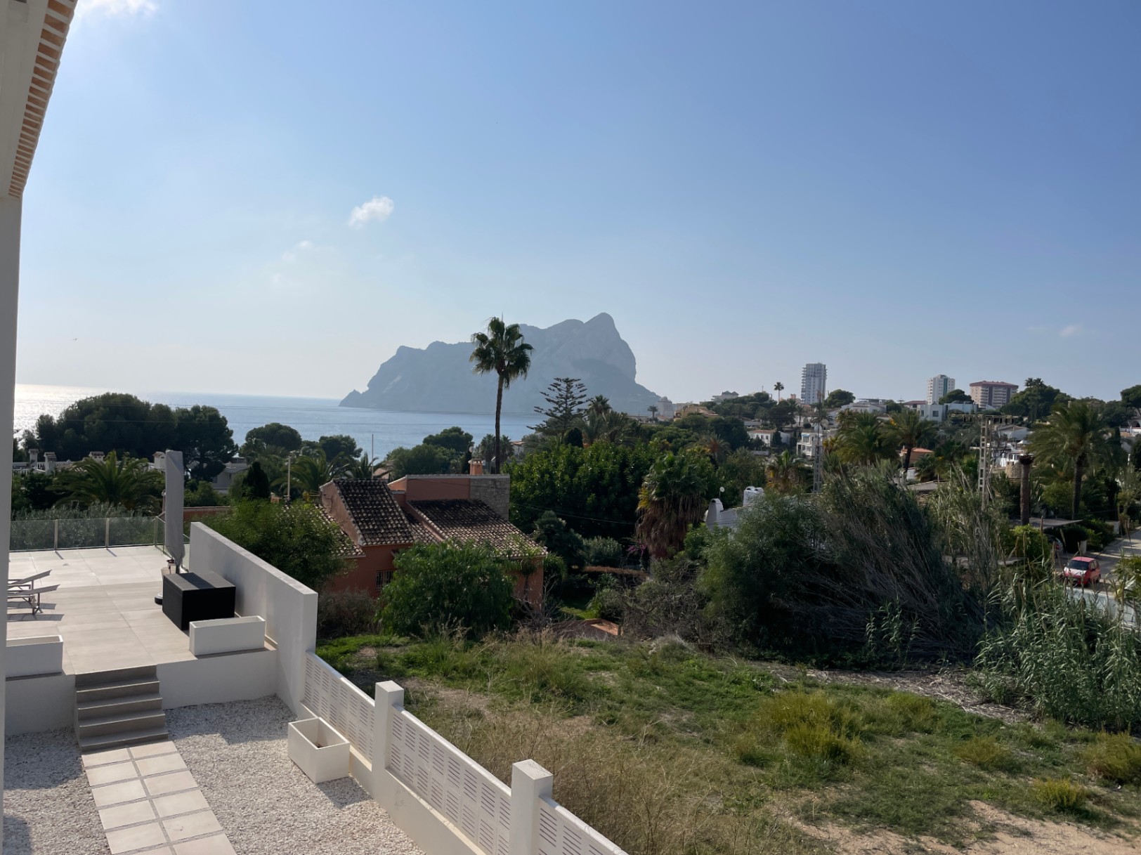 Panoramablick auf den Peñón de Ifach und das Mittelmeer von einer modernen Terrasse mit hellen Fliesen, eingebettet in die grüne Landschaft von Calpe.