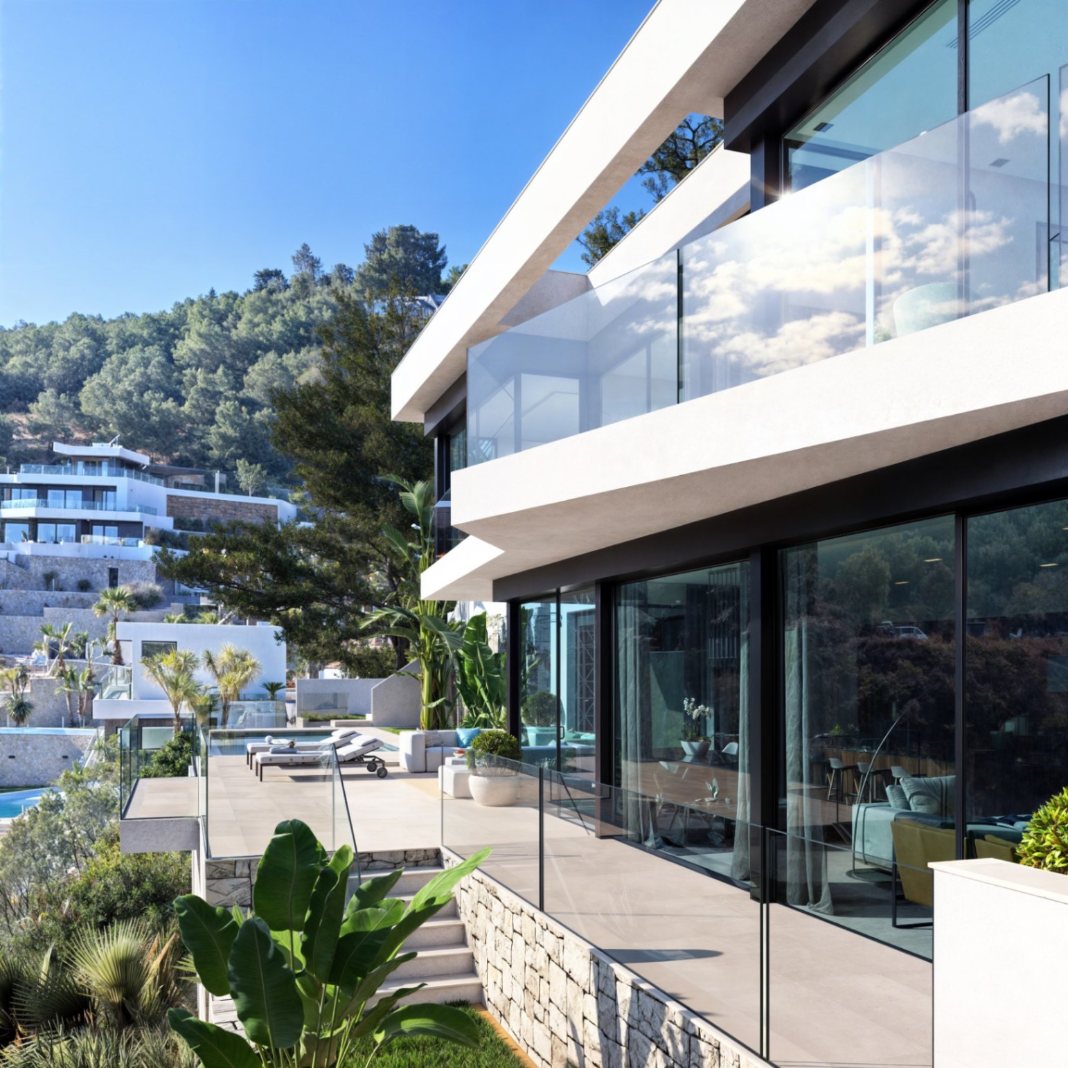 Moderne zweistöckige Fassade mit bodentiefen Glasfronten, Glasgeländern und Natursteinmauern, eingebettet in eine mediterrane Gartenlandschaft.