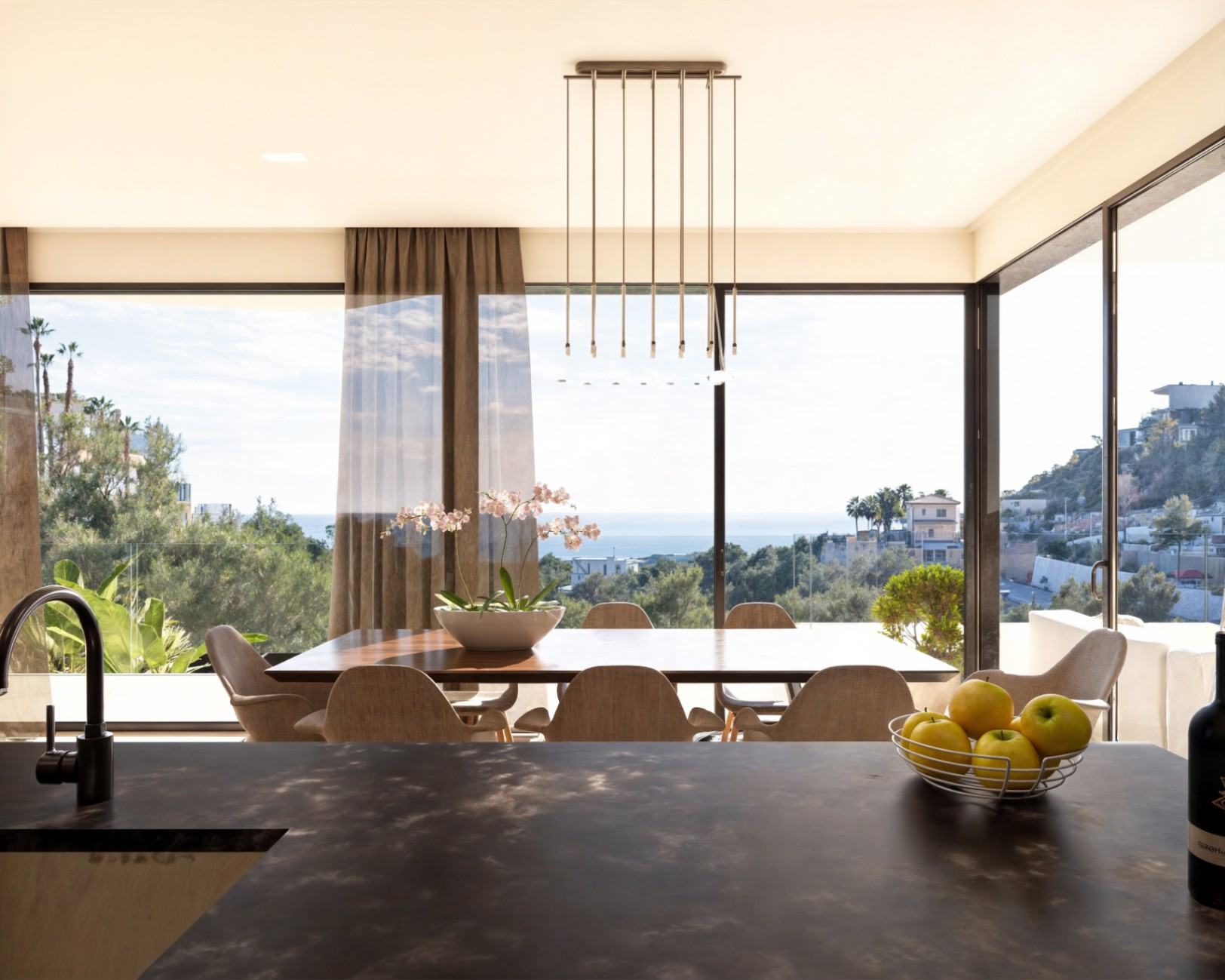 Offener Essbereich mit großem Holztisch und moderner Pendelleuchte, ergänzt durch bodentiefe Fenster mit Panoramablick auf das Mittelmeer.
